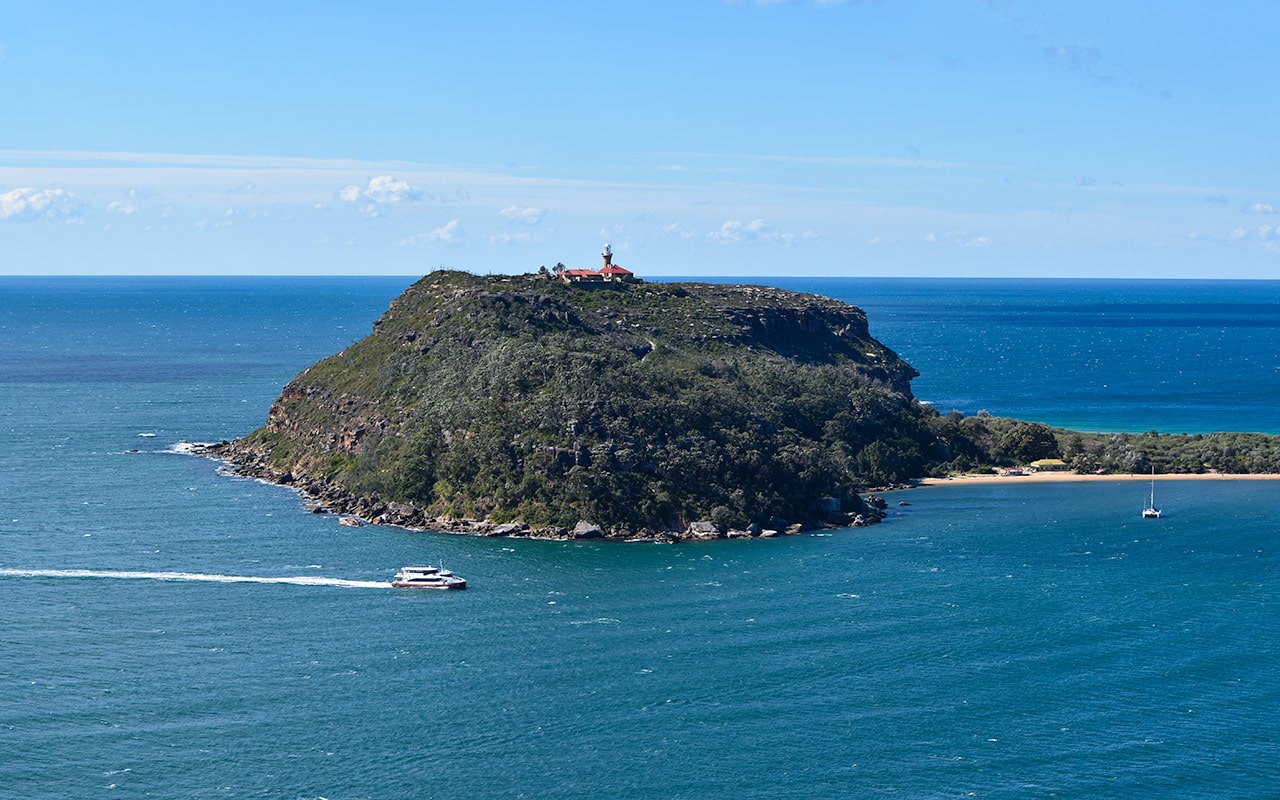 The red roof of the Barrenjoey Lighthouse is clearly visible from West Head Lookout